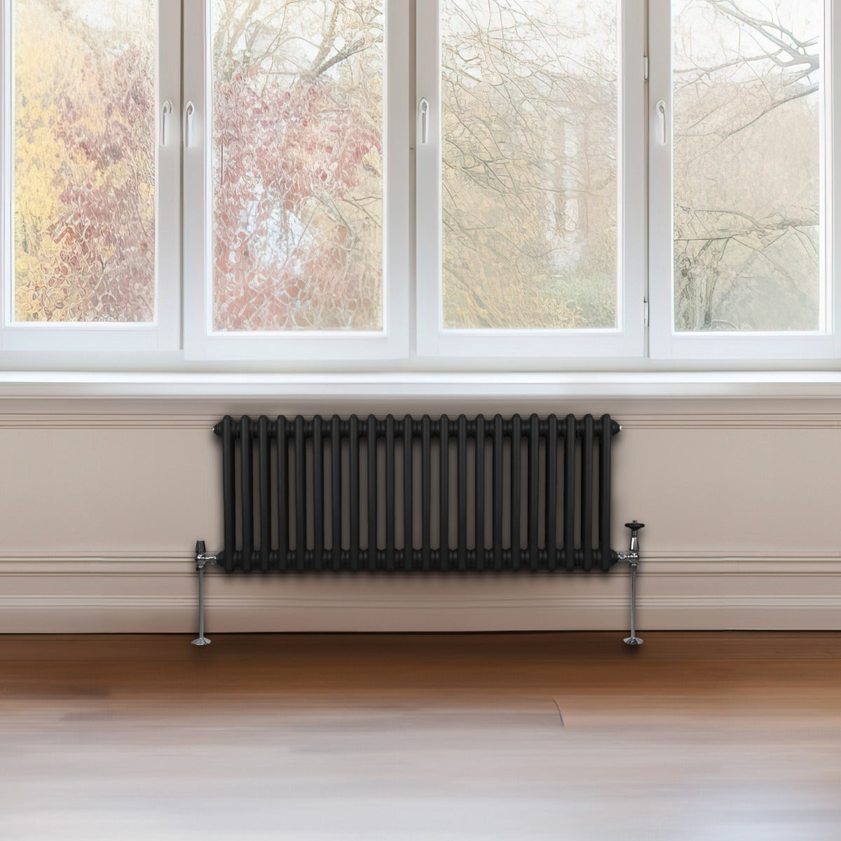 Traditioneller 2-Spalten-Heizkörper in Schwarz, 300 x 1012 mm, mit glänzender Oberfläche und eleganten, runden Rohren, vor einem großen Fenster platziert