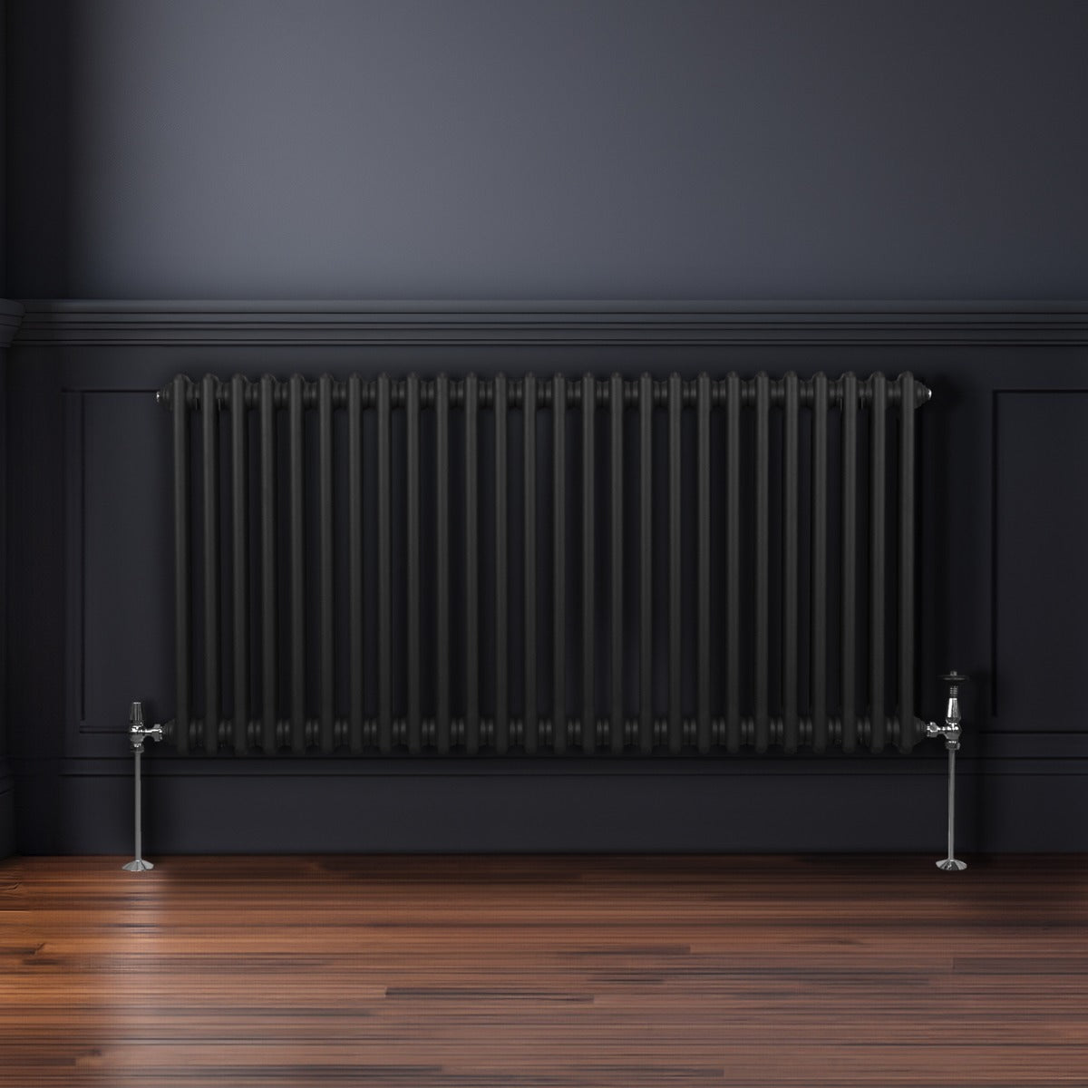 Traditioneller 2-Spalten-Heizkörper in Schwarz, 600 x 1192 mm, mit glänzenden Metallfüßen, vor einer dunklen Wand und auf einem Holzfußboden