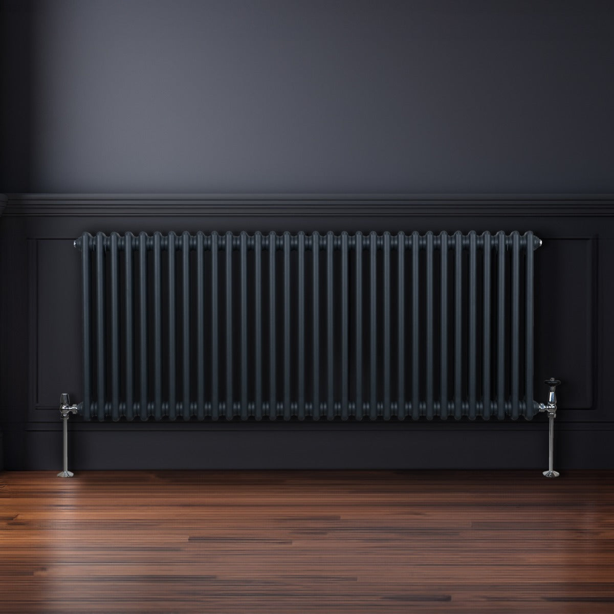 Traditioneller 2-Spalten-Heizkörper in Anthrazitgrau, 600 x 1462 mm, mit vertikalen Lamellen und glänzenden Füßen, vor einer dunklen Wand auf Holzfußboden