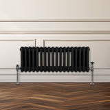 Traditioneller 3-Spalten-Heizkörper in Schwarz, aus robustem Metall, mit glatter Oberfläche und elegantem Design, montiert an einer Wand über einem Holzfußboden