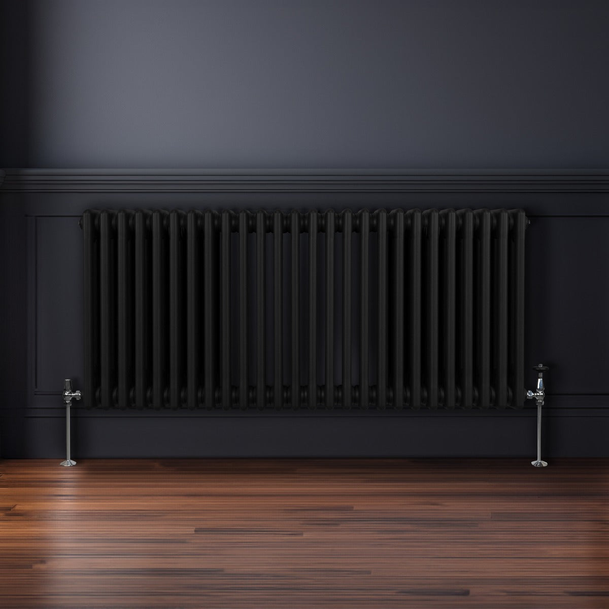 Traditioneller 3-Spalten-Heizkörper in Schwarz, 600 x 1192 mm, mit glänzenden Metallventilen, vor einer dunklen Wand und auf einem Holzfußboden