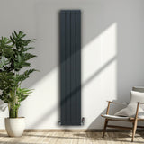 Anthrazitgrauer Aluminium Paneelheizkörper mit schlankem Design, 1800mm x 315mm, montiert an einer hellen Wand, umgeben von Pflanzen und einem Stuhl