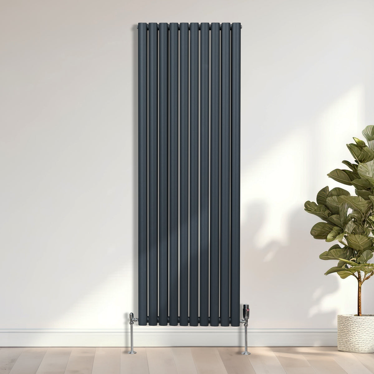 Elegantes Chrom-Thermostatventil an einem schlanken, vertikalen Heizkörper in einem modernen Raum mit hellen Wänden und Pflanzen im Hintergrund