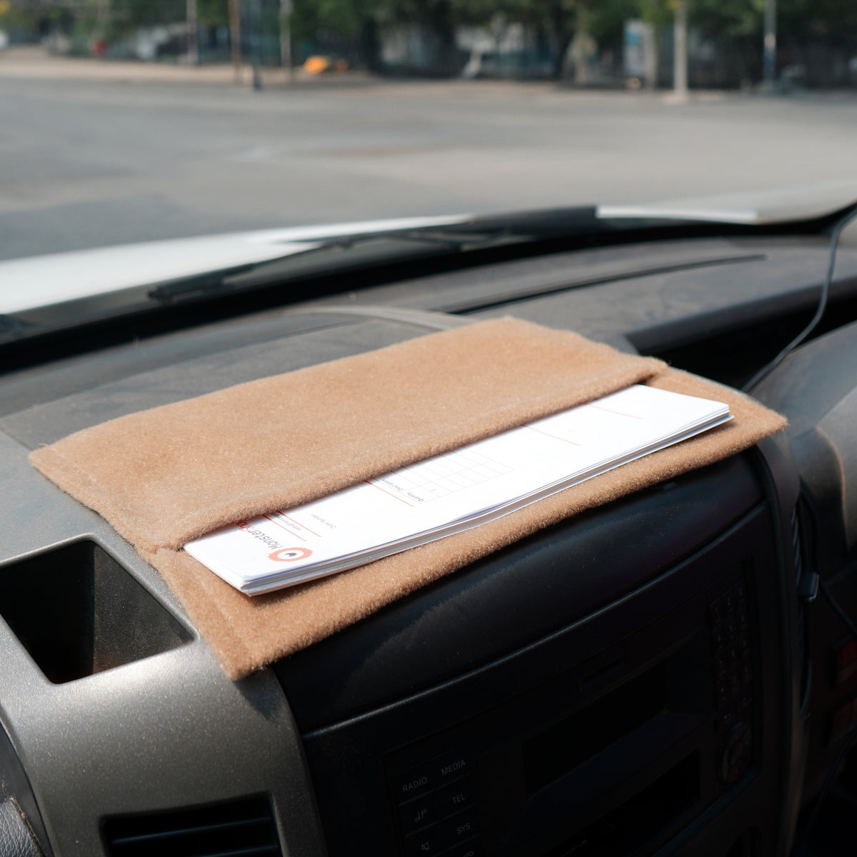 Beige Autostoff mit weicher, samtiger Textur, auf dem Armaturenbrett platziert, hält Dokumente sicher und ordentlich