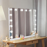 LED Bluetooth Spiegel in Weiß, 80 x 60 cm, mit runden, dimmbaren Lichtern, ideal für Make-up und persönliche Pflege, elegant auf einem Holzschreibtisch platziert