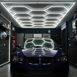 Hexagon LED Lampe mit modernem Design, strahlend weißem Licht, montiert an einer stilvollen Decke in einer eleganten Garage mit einem blauen BMW