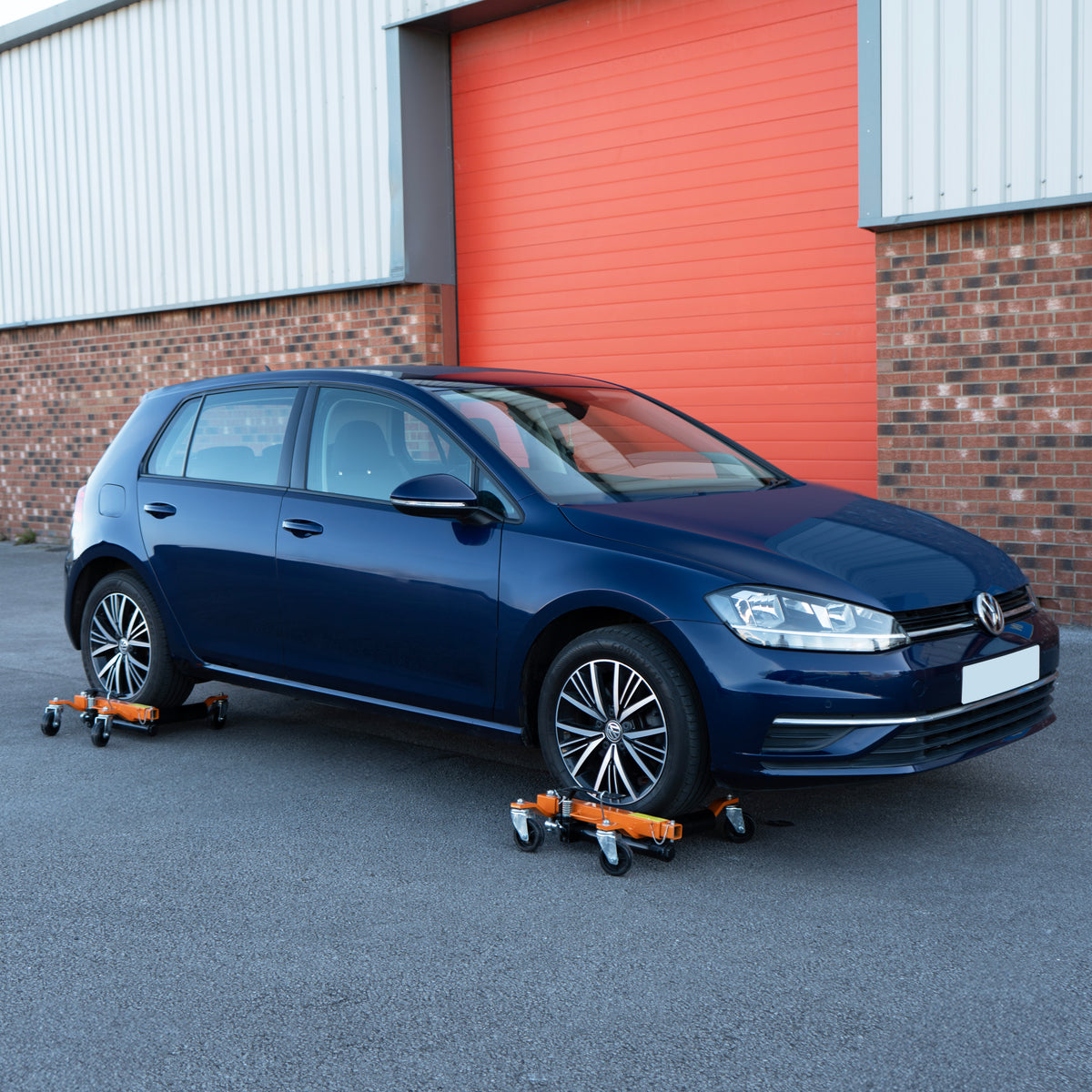 Hydraulischer Positionierungsschlitten unter einem blauen Volkswagen Golf, ausgestattet mit robusten Rollen und orangefarbenen Halterungen für einfache Mobilität