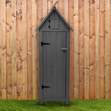 Grau lackierter Gartenschrank aus Holz mit spitzem Dach, stabilen Scharnieren und einem kleinen oberen Fach, vor einer Holzlattenwand platziert