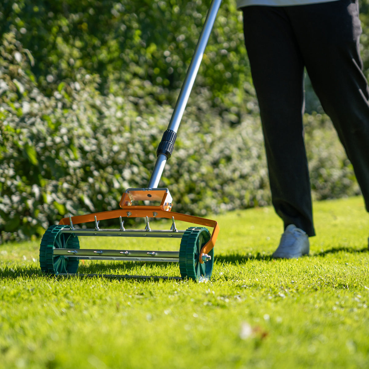 Grüner T-Mech Rasenrakel mit 50 cm breiter Arbeitsfläche, robustem Metallrahmen und rollenden Lüfterrädern auf saftigem Rasen