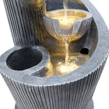 Elegante elektrische Wasseranlage "Spiral Springs" aus grauem Stein mit strukturierten Oberflächen und sanft fließendem Wasser in runden Schalen