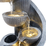 Elegante elektrische Wasseranlage "Spiral Springs" mit drei runden Schalen, die sanft Wasser abgeben, in dunklem Steinoptik und warmem Licht