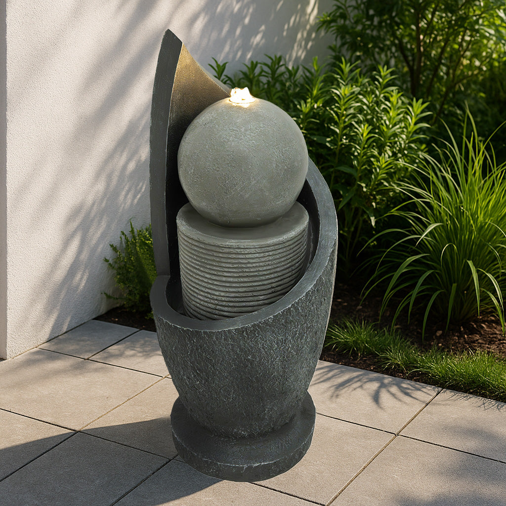 Elegante elektrische Wasseranlage "Zen Cascade" aus grauem Stein, mit geschwungenen Formen, einer runden Kugel und sanft fließendem Wasser, ideal für Garten und Terrasse