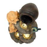 Zwei niedliche Hundeskulpturen aus Kunststein, die an einer Wasseranlage mit einem antiken Krug und sanft fließendem Wasser sitzen, umgeben von goldenen Lichtern