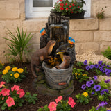 Zwei Otter spielen in einer Wasseranlage mit rustikalem Design, umgeben von bunten Blumen und einer grünen Pflanze, die lebendige Farben und Texturen bieten