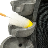 Graue elektrische Wasseranlage "Sleek Streams" mit mehreren Schalen, die von einem weißen Pinsel gereinigt werden, um die Textur und Details zu betonen