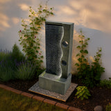 Elegante elektrische Wasseranlage "Harmony Falls" aus grauem Stein mit sanft fließendem Wasser, umgeben von grünen Pflanzen und Lavendel