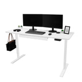 Moderner elektrischer Stehschreibtisch in Weiß mit Schublade, zwei Monitoren, Tastatur, Pflanzen und Tasche, ideal für ergonomisches Arbeiten