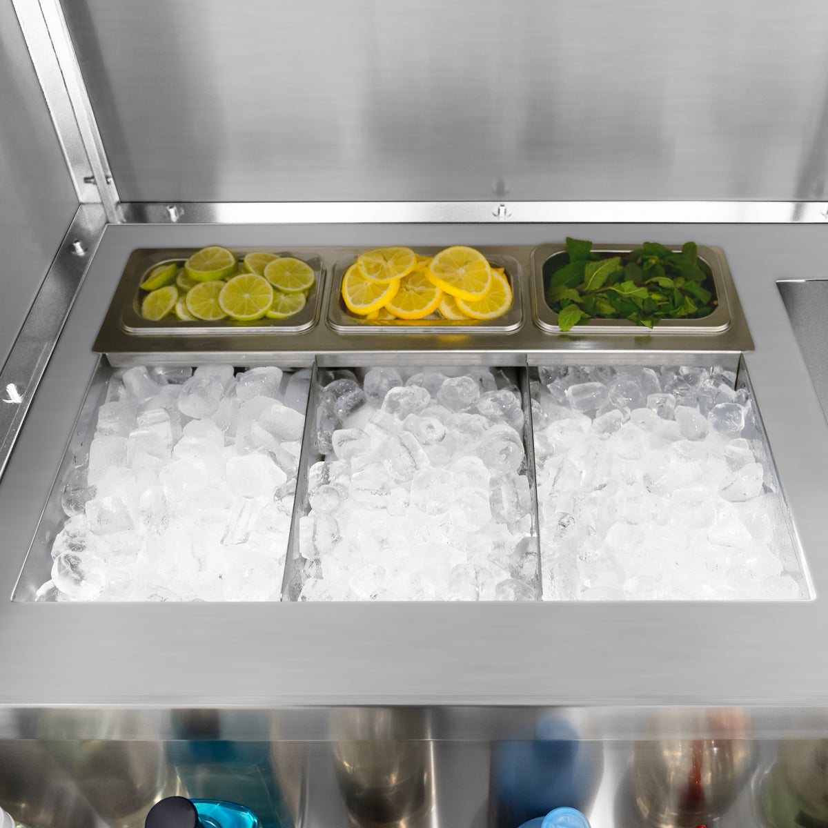 Kühle Cocktailbar-Station mit drei Fächern: Eiswürfel, frische Limetten- und Zitronenscheiben sowie Minzblätter in Edelstahlbehältern