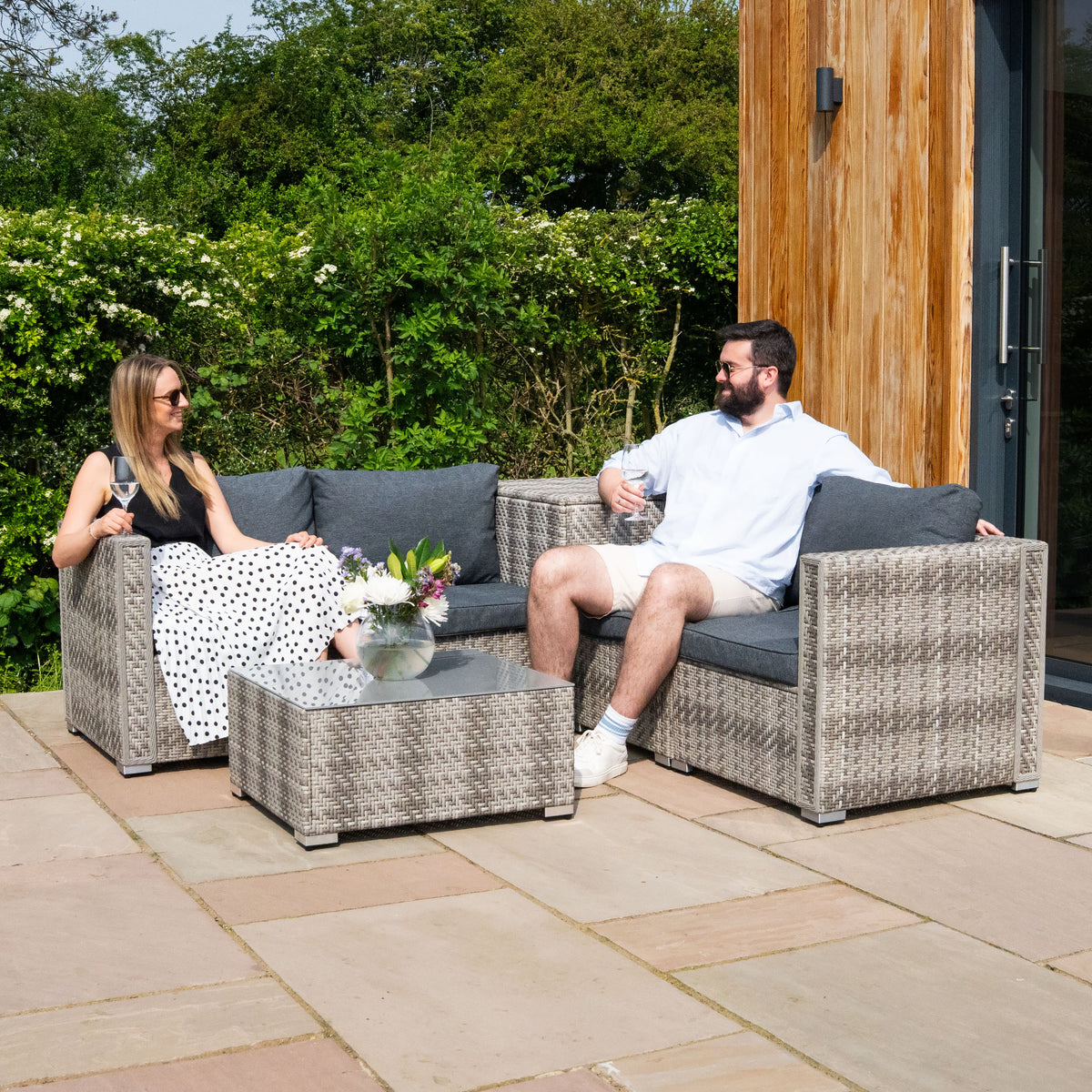 Sechsteiliges Rattan-Möbelset in Grau, bestehend aus zwei Sofas und einem Tisch, mit bequemen, grauen Kissen, ideal für den Außenbereich