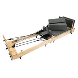 Pilates Reformer Maschine aus Eiche mit grauen Polstern, verstellbaren Riemen und stabiler Bauweise für effektives Training