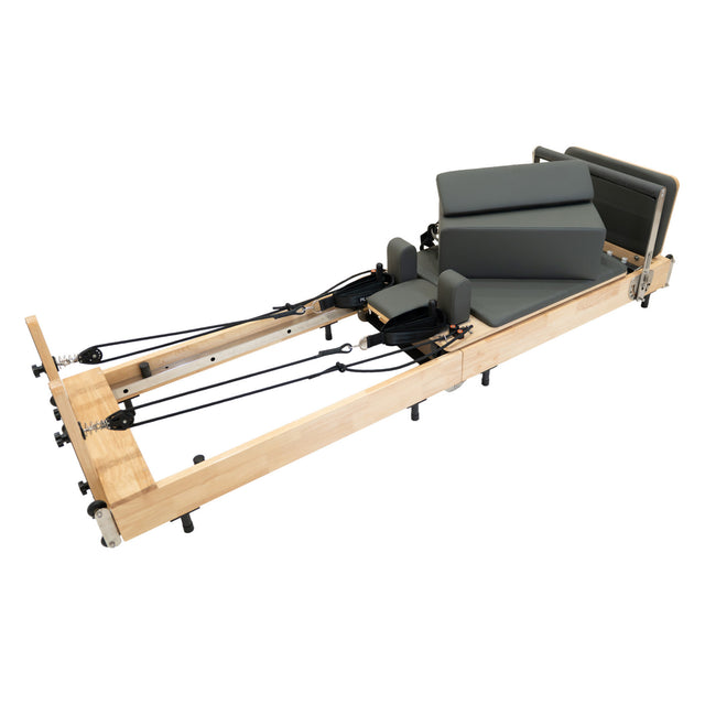 Pilates Reformer Maschine aus Eiche mit grauen Polstern, verstellbaren Riemen und stabiler Bauweise für effektives Training