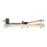 Pilates Reformer Maschine aus Eiche mit grauem Polster, stabiler Bauweise und verstellbaren Widerstandselementen für effektives Training