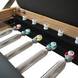 Pilates Reformer Maschine aus Eiche mit grauem Polster, verstellbaren Federn in verschiedenen Farben und robustem, modernem Design