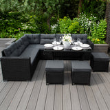Schwarze Gartenmöbel mit gepolsterten Kissen, eleganter Essbereich im Freien, umgeben von grünen Pflanzen und Blumen, stilvoll und modern
