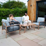 Elegante 4-teilige Aluminium-Sofagarnitur mit hellblauen Kissen, Holzdetails und einer schwarzen Rattan-Aufbewahrungsbox im Freien, ideal für entspannte Momente