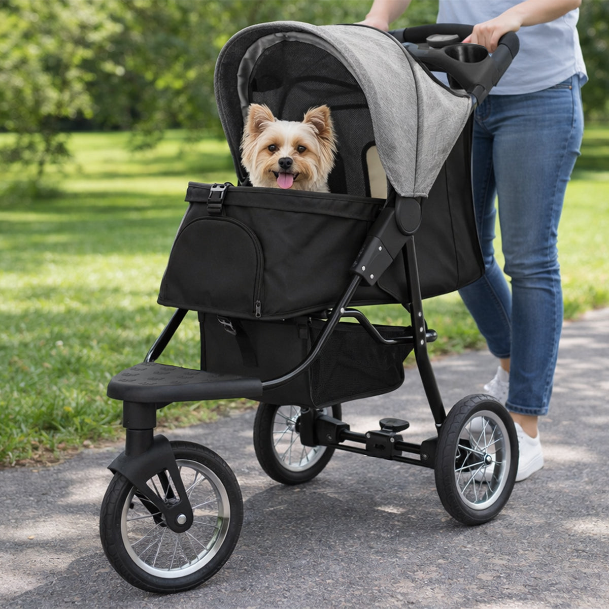 Haustier-Buggy in Grau mit schwarzem Korb, ideal für kleine Hunde, auf einem Weg im Freien, mit einer Person, die ihn schiebt