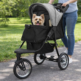 Haustier-Buggy in Grau mit schwarzem Korb, ideal für kleine Hunde, auf einem Weg im Freien, mit einer Person, die ihn schiebt
