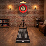 Schwarzer Dartboard-Teppich mit weißen Zahlen und einem roten Dartboard an einer Backsteinwand, umgeben von warmem Licht und Holzfußboden