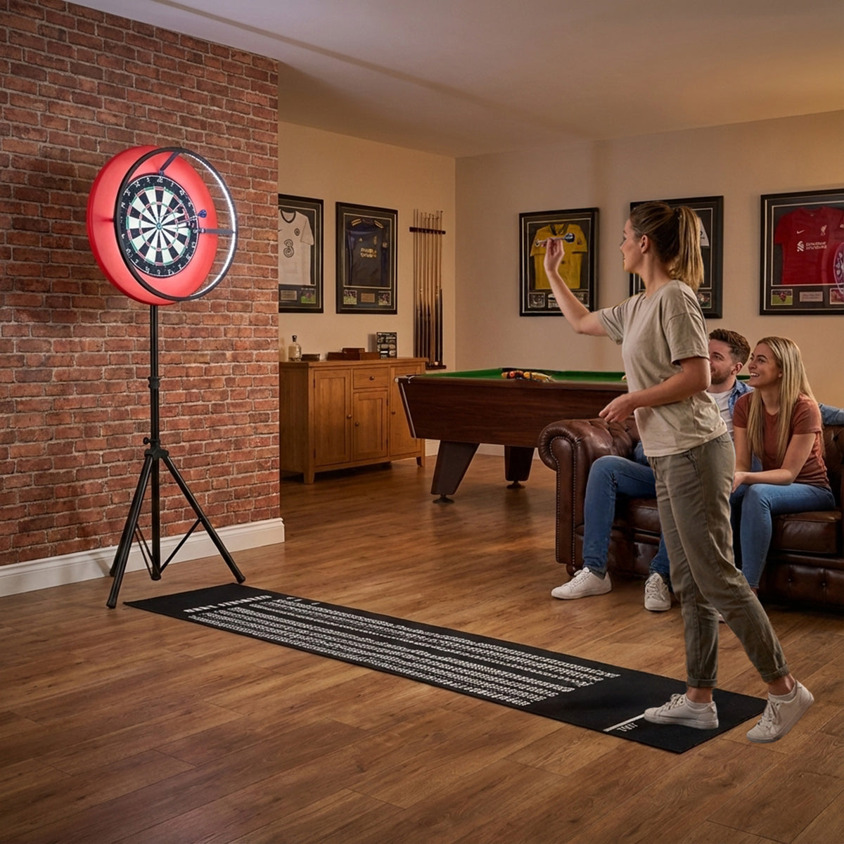 Dartspielende Frau vor einem beleuchteten Dartboard mit rotem LED-Ringlicht, umgeben von Freunden in einem gemütlichen Raum mit Holzfußboden