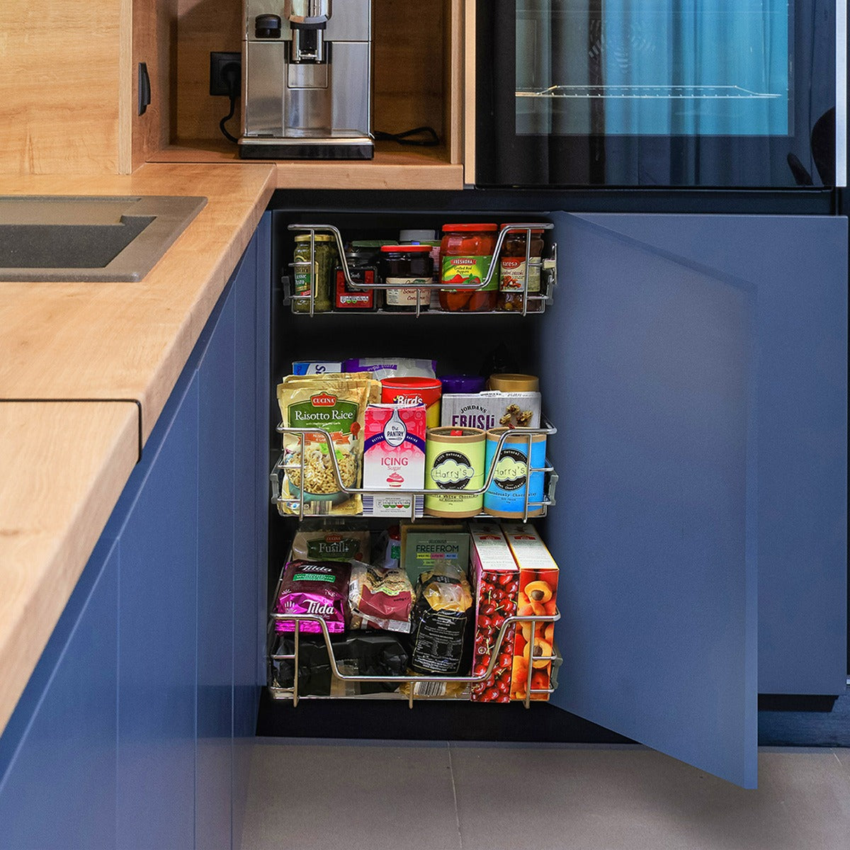 Zwei ausziehbare Küchenschubladen aus Edelstahl, in einem blauen Schrank, gefüllt mit verschiedenen Lebensmitteln und Gewürzen, praktisch und platzsparend