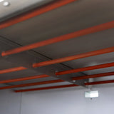 Metallregale mit orangefarbenen Stangen im Inneren eines großen gewerblichen Pizza- und Backofens, ideal für die Aufbewahrung von Backblechen und Zubehör