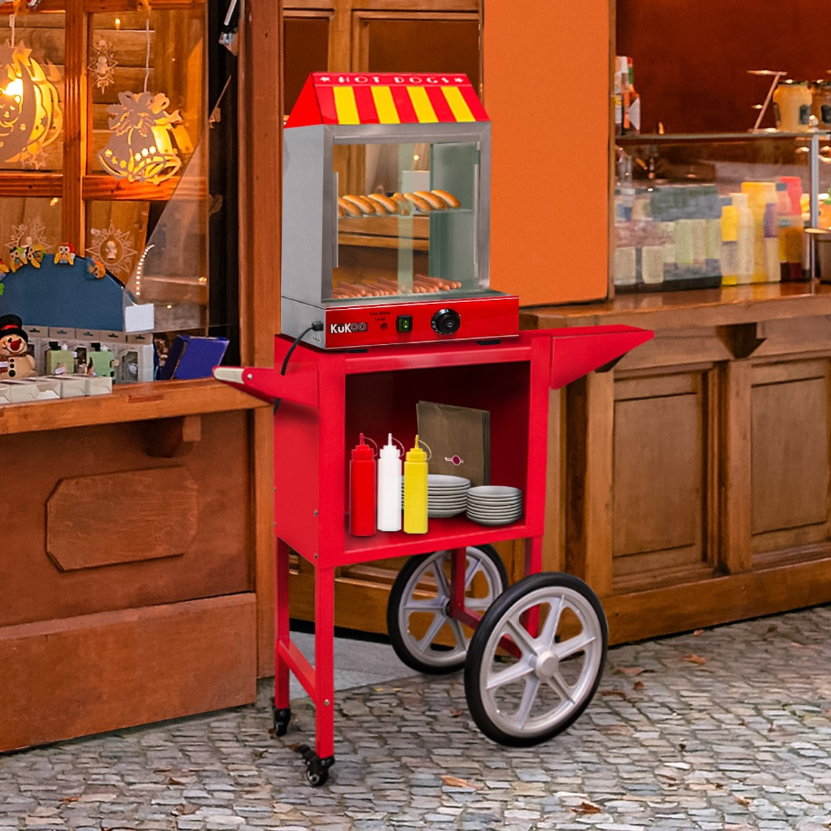 Roter KuKoo Hot Dog Wärmer mit Wagen, ausgestattet mit einem transparenten Sichtfenster, Senf- und Ketchupflaschen sowie Tellern auf einem stabilen Gestell