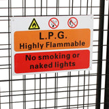 Warnschild in orange und rot, das auf die hohe Entflammbarkeit von LPG hinweist, mit Symbolen für Rauchverbot und offene Flammen, vor einem Gitterzaun