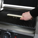 Ein Handgriff mit einer Holzbürste reinigt die geriffelte Grillfläche des KuKoo Panini Grills, der aus robustem Edelstahl gefertigt ist