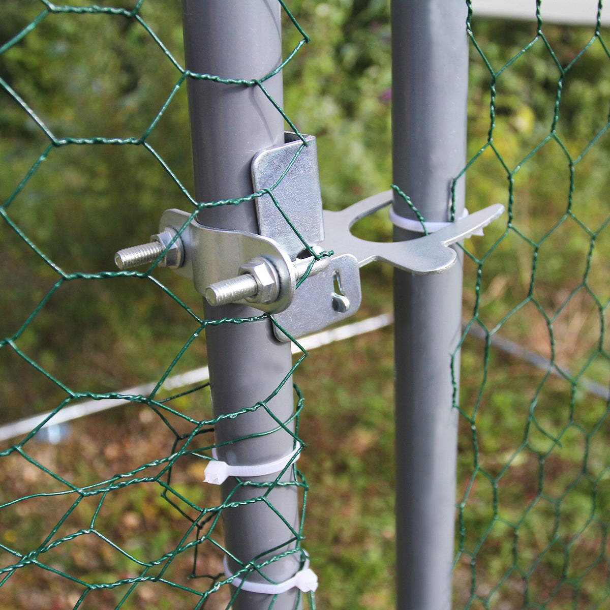 Metallischer Verschluss für Hühnerzaun, graue Pfosten mit grünem Drahtgeflecht, stabil und wetterfest, ideal für Freilaufgehege