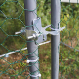 Detailansicht einer stabilen Metallbefestigung für einen Hühnerfreilauf, die das Netz sicher an einem grauen Pfosten fixiert, um Schutz zu bieten
