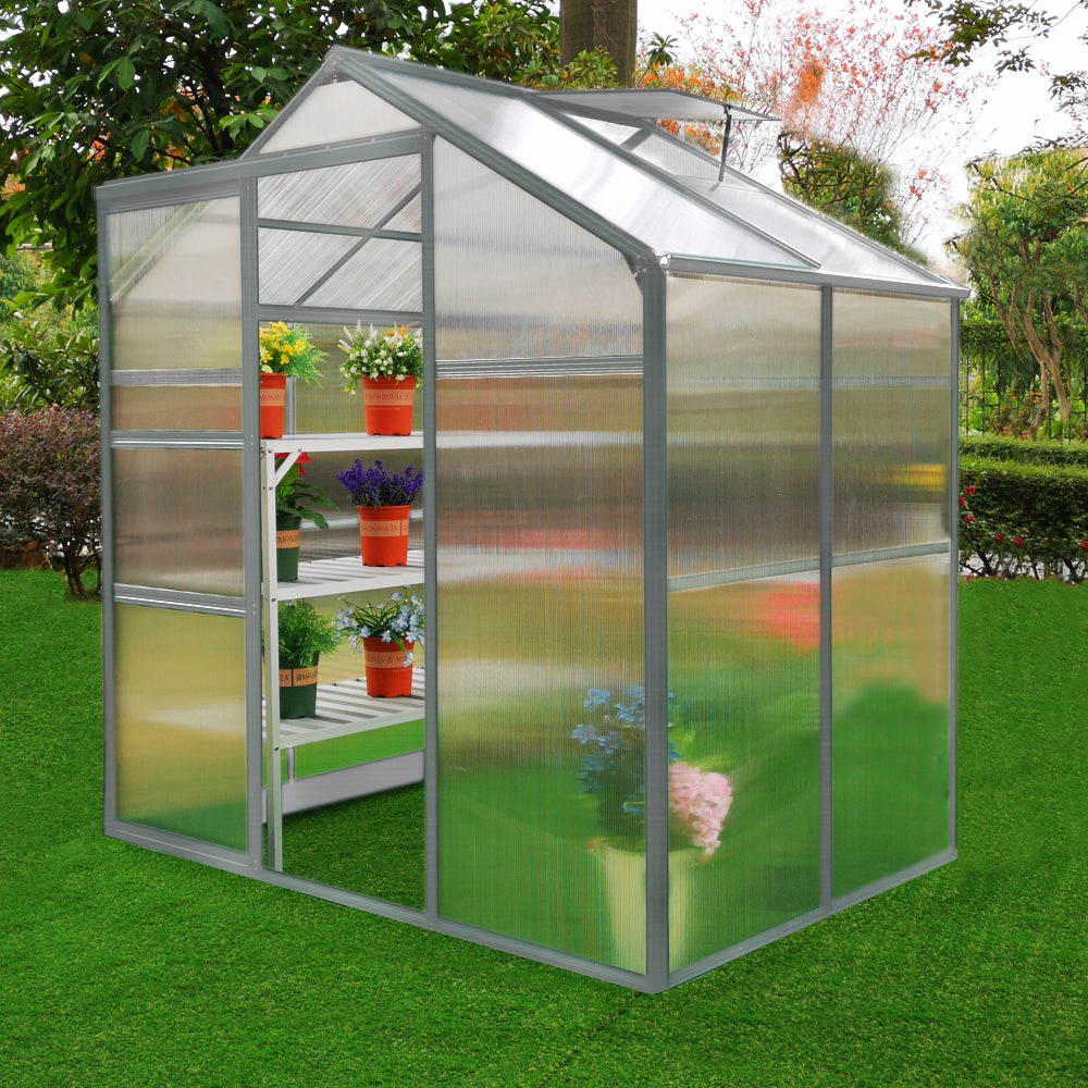 Gewächshaus 1.8m x 1.2m ohne Boden mit transparenten Wänden, weißen Regalen und bunten Blumentöpfen, umgeben von grünem Rasen und Pflanzen