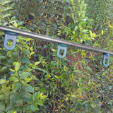 Grüne Pflanzen im Hintergrund, ein stabiler Metallrahmen mit blauen Halterungen, ideal für das Gewächshaus 1.8m x 1.8m ohne Boden
