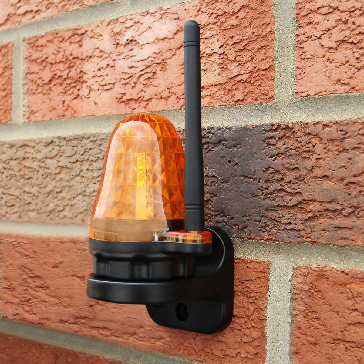 Leuchtendes oranges Warnlicht mit Antenne, montiert an einer Ziegelwand, bietet Sichtbarkeit und Sicherheit für den elektrischen Torantrieb