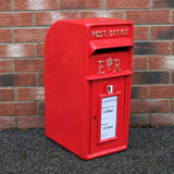 Roter Briefkasten mit Bodenständer, glänzende Oberfläche, klassische Form, mit Post Office Aufschrift und abnehmbaren Sammelzeiten auf einem Ziegelstein-Hintergrund