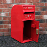 Roter Briefkasten mit Bodenständer, glänzende Oberfläche, goldene Buchstaben "ER" und "POST OFFICE", offen für den Briefversand, vor einer Ziegelwand