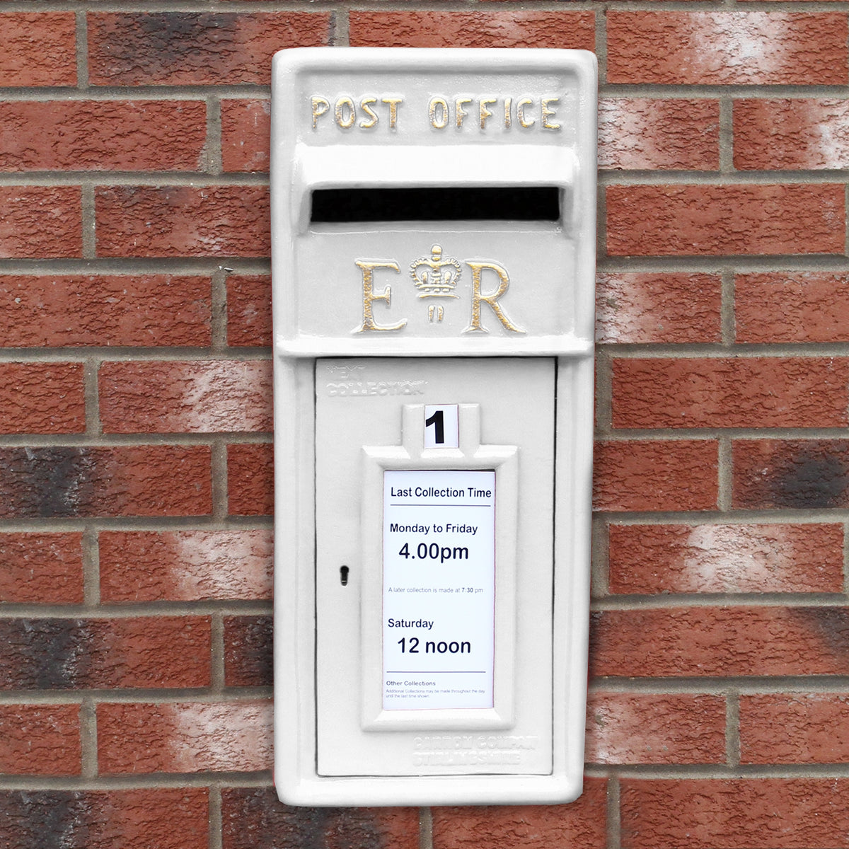 Weißer Briefkasten mit Bodenständer, dekoriert mit königlichem Wappen, auf Ziegelmauer, mit Sammelzeiten für Postzustellung