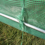 Grünes Netzmaterial des Polytunnels mit 19 mm Durchmesser, stabilisiert durch silberne Metallstangen, auf grünem Grasboden platziert