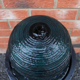 Schwarzer Kugelbrunnen mit gewellter Oberfläche, glänzendem Wasser und runder Form, ideal für Garten- und Terrassengestaltung