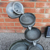 Grauer Solar Kaskadenbrunnen mit Akku, bestehend aus mehreren Töpfen, die Wasser sanft abgeben, auf einem stabilen Gestell, ideal für Garten oder Terrasse