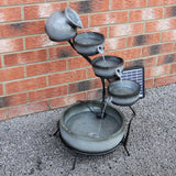 Eleganter grauer Solar Kaskadenbrunnen mit Akku, der Wasser in mehreren Schalen fließen lässt, auf einem stabilen schwarzen Gestell platziert